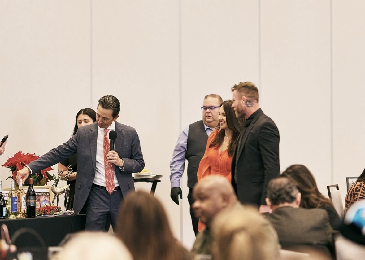Nathan Waits at a live event beside a speaker on stage