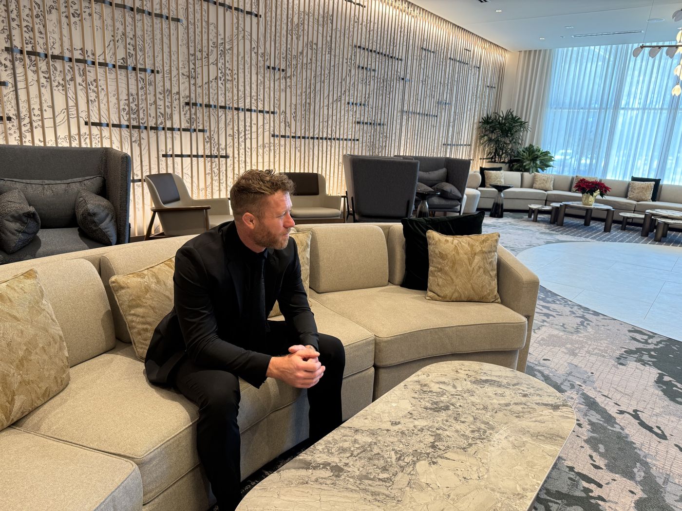 Nathan Waits seated in a hotel lobby in a black suit