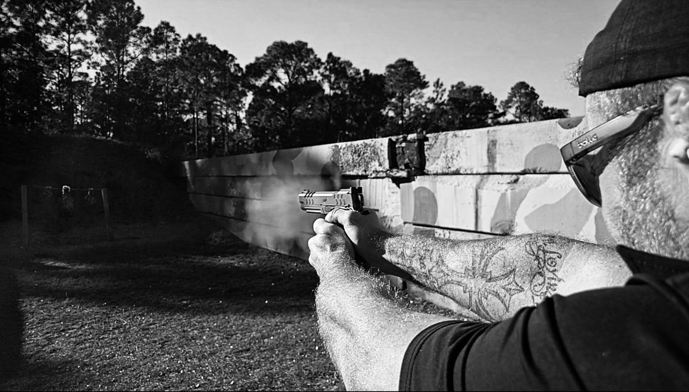 Live-fire pistol training at an outdoor range, black and white